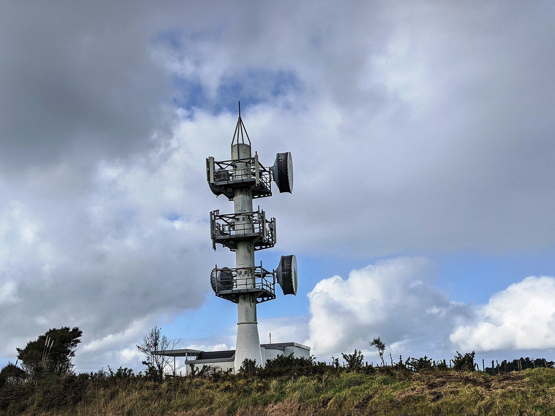 Torre de telecomunicações com antenas sob céu nublado